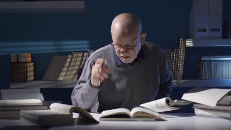 Close-up-shot-of-senior-old-man-in-glasses-holding-and-reading-an-old-book.